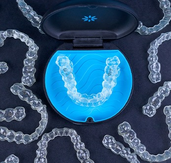 Bird’s eye view of several Invisalign trays on black surface