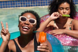 two teens eating popsicles in a swimming pool