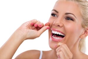 Smiling woman flossing her teeth